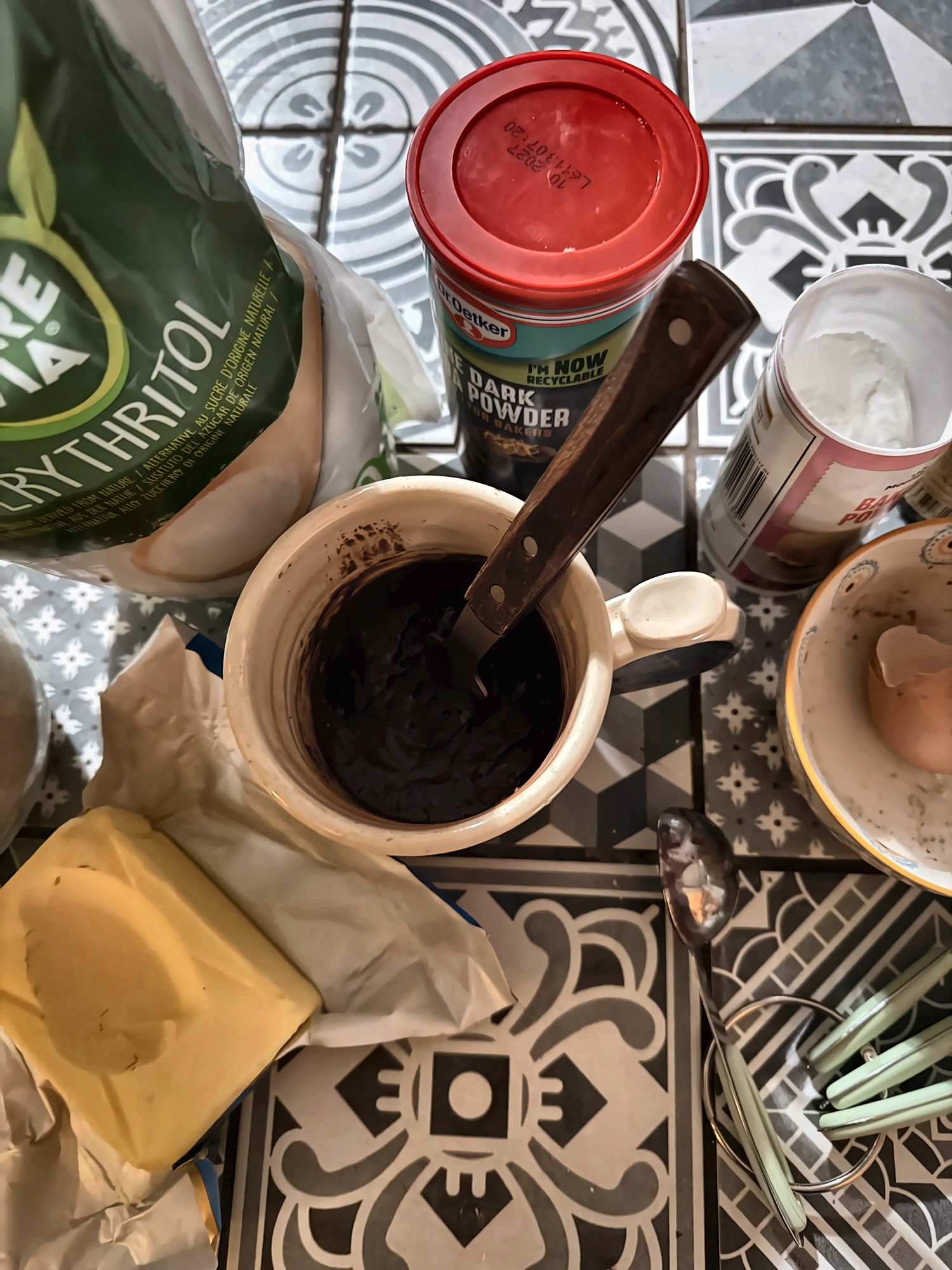 The mixed chocolate batter in the mug, with erythritol, cocoa powder and butter around it